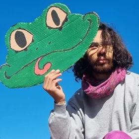 Vie, une grenouille en carton devant le visage